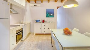 Une cuisine compacte avec des meubles blancs, un four encastré et un coin repas comprenant une table et des chaises.