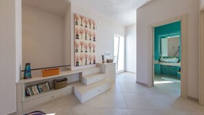 Un vaste espace de vie avec un escalier menant à un balcon, une bibliothèque et une vue sur la cuisine.