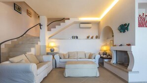Un salon moderne avec un escalier, une cheminée et un ensemble de canapés.