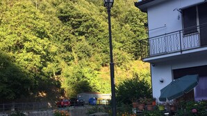 A rustic outdoor seating area with a bench and a statue, surrounded by potted plants and a white picket fence. - House in the woods Osiglia, Liguria (Osiglia)