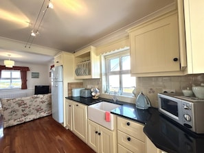 A compact kitchen with white cabinets, a black countertop, and a window providing natural light.