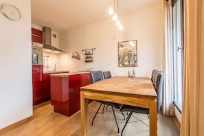 A compact kitchen with a red island, a dining table with chairs, and a large window with curtains. - Excellent value for money, Balme 3b is a modern 2 bedroom apartment located in Chamonix Sud. (Chamonix-Mont-Blanc)