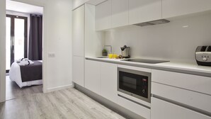 Una cocina moderna con armarios blancos, horno empotrado y cafetera.