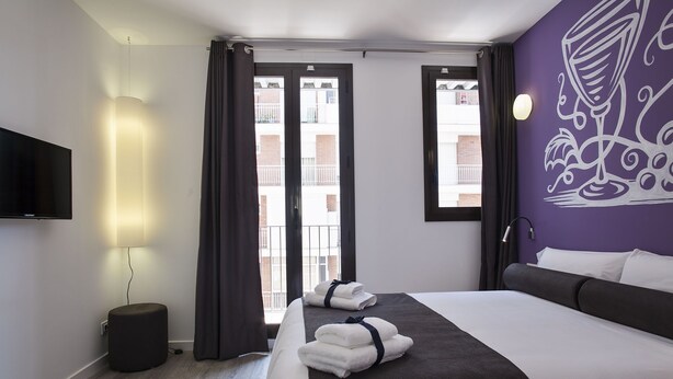 Una habitación de hotel con cama, televisión, lámpara y vistas al exterior.