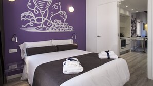 Una habitación de hotel con una cama grande, un baño visible a través de una puerta abierta y un mural en la pared.
