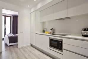 A modern kitchen with white cabinetry, a built-in oven, and a microwave.