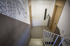 A staircase with a handrail leading to a door with a vent.