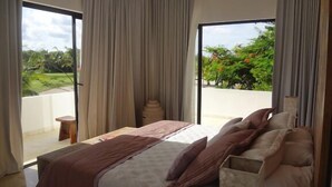 Ein Schlafzimmer mit einem großen Bett, einem kleinen Tisch und Blick auf Grünfläche.