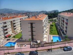 Stunning residential building with a central tower and balconies, surrounded by a lush lawn and a swimming pool.