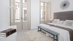 Ein Schlafzimmer mit einem großen Bett, einem Nachttisch, einer Bank und einem Fenster mit Blick nach draußen.
