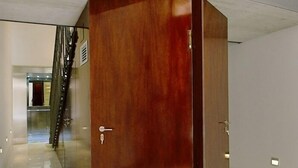 Eine Holztür mit Schlüsselloch, Glasfenster und Metallbeschlag.