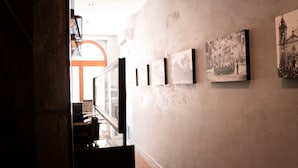 A hallway with framed pictures on the wall, a window with a view, and a door leading to another room. - Quaint Boutique Hotel Sannat (Sannat)