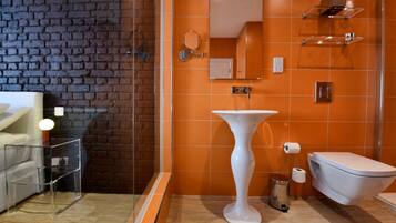 Une salle de bain avec un lavabo sur colonne blanc, des toilettes et une douche à parois de verre.