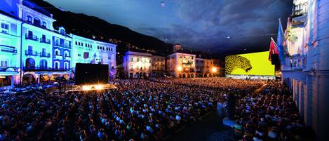 A large outdoor gathering in a city square with buildings in the background.