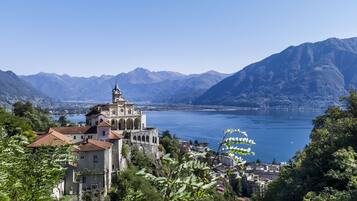 A historic building with a clock tower, overlooking a lake and mountains.