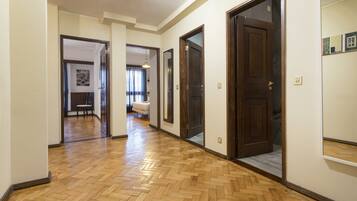 A hallway with wooden flooring, multiple doors, and a light fixture.
