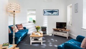 A modern living room with a blue sofa, a coffee table, a television, and a fireplace.