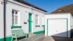 A building with a green door, a bench, and a white garage door.