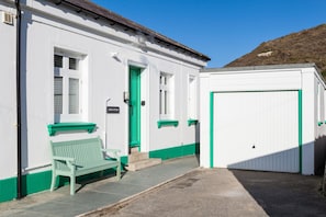 Een gebouw met een groene deur, een bank en een witte garagepoort.