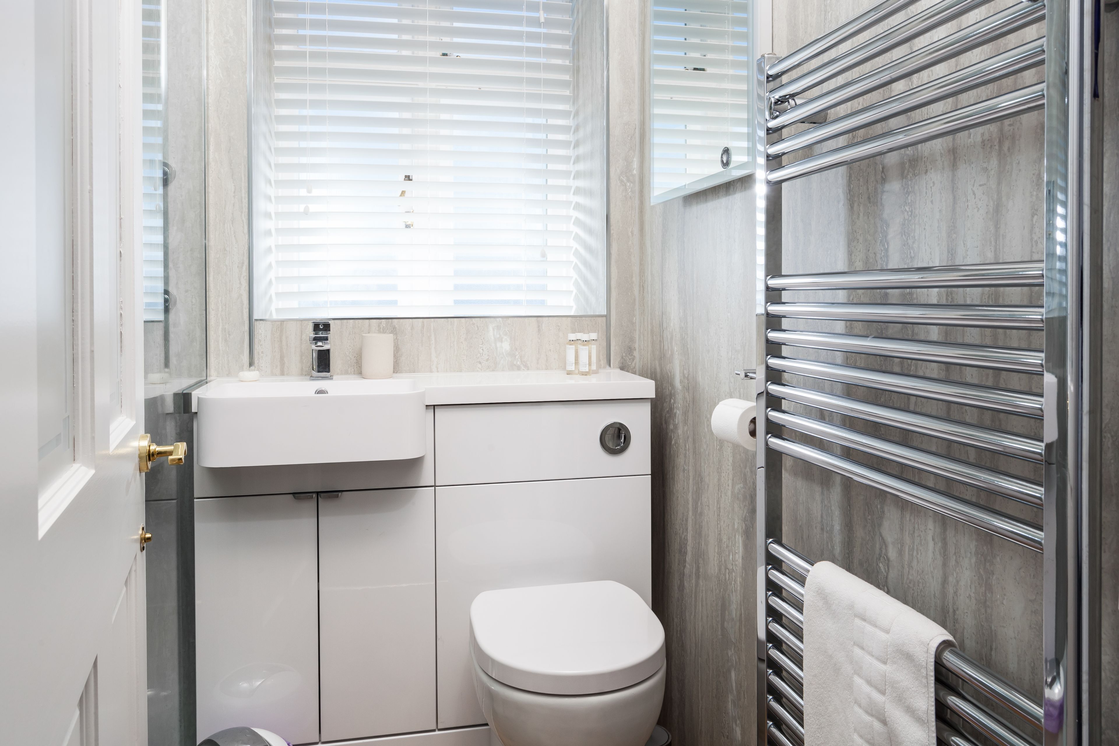 A bathroom with a toilet, sink, and towel rack.