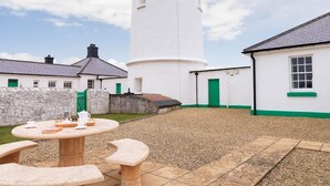 A courtyard with a white tower, stone walls, and a round table with benches. - Ariel, Marcross, Llantwit Major , Vale of Glamorgan, Wales (Marcross)
