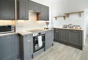 A modern kitchen with grey cabinetry, a built-in oven, and a microwave.