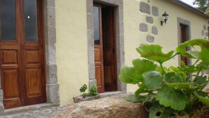 A stone building with two wooden doors and a small window. - Casa Rural Las Caldereras (Teror)