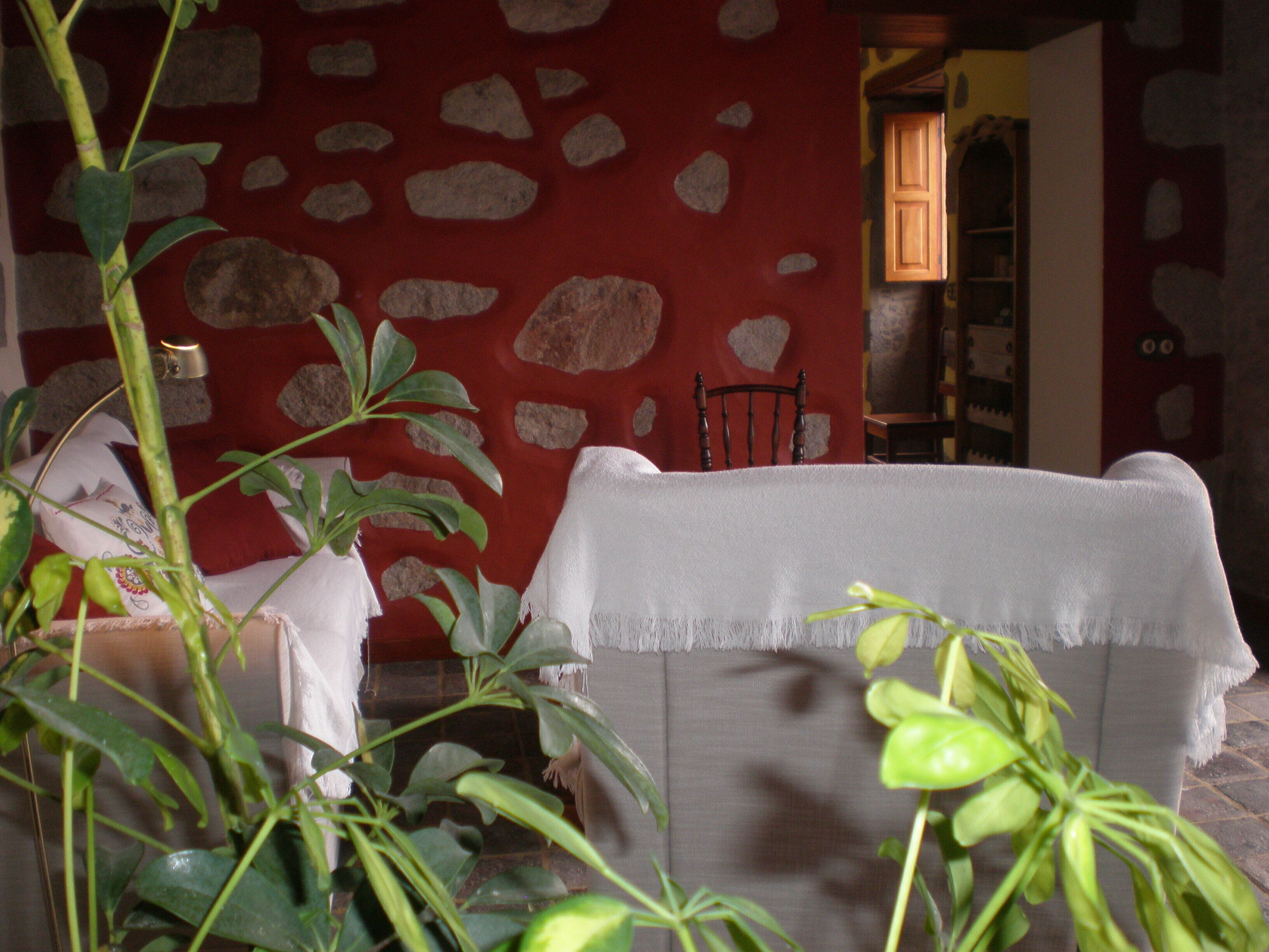 A room with a stone wall, a chair, and a plant.