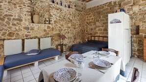 Una habitación con paredes de piedra, una cama y una mesa lista para comer, junto a un armario blanco.