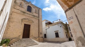 Una calle estrecha con un edificio que presenta una gran puerta de madera y un ventanal pequeño.