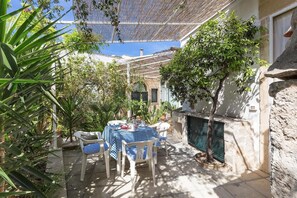An outdoor patio with a checkered table and chairs, surrounded by plants and a pergola. - Casa Messapica - Mono by Barbarhouse (Ugento)