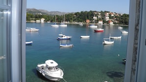 Une vue sur un port où sont amarrés de nombreux bateaux, avec une eau claire et une colline en arrière-plan, parsemée de bâtiments.