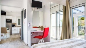 Ein modernes Hotelzimmer mit Bett, Schreibtisch mit rotem Stuhl, Fernseher und Balkon mit Aussicht.