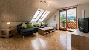A modern living room with a sofa, coffee table, and TV, featuring a wooden floor and a patterned wall.