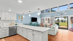 A spacious kitchen with white cabinets, a large island, and a dining area with a view of the outdoors. - Unit 71, Catch of The Day, 3 Bedroom Beach Condo (Panama City Beach)