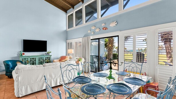 A dining area with a table set for four, surrounded by chairs with blue woven placemats. - Unit 71, Catch of The Day, 3 Bedroom Beach Condo (Panama City Beach)