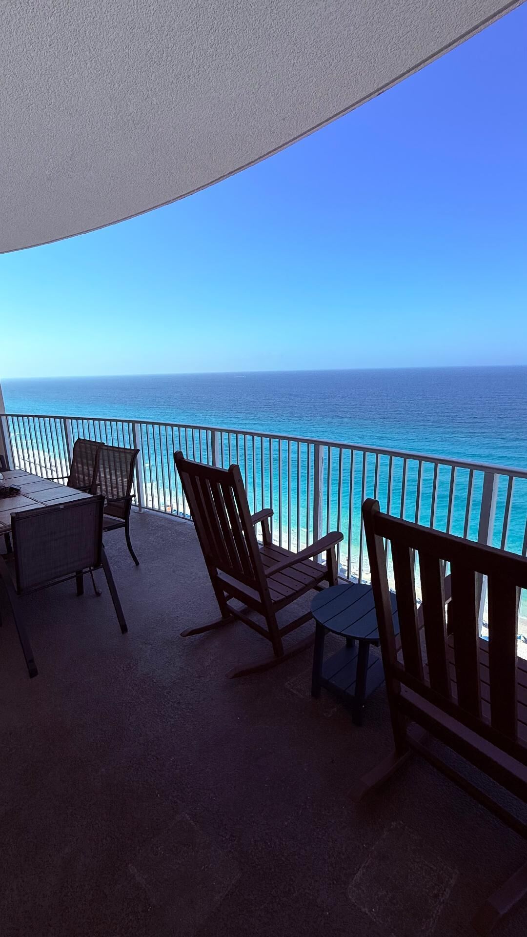 A balcony with a view of the ocean, equipped with a table and chairs.