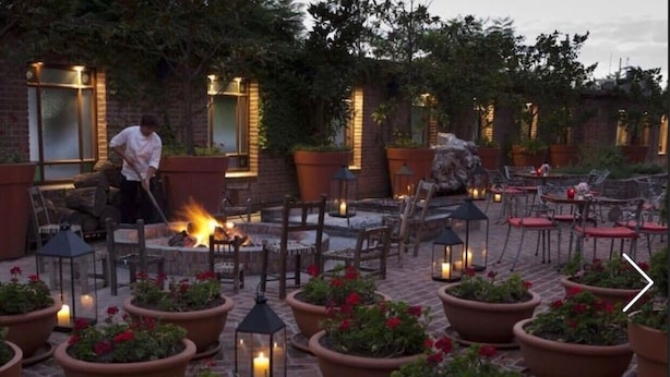 Un espace extérieur aménagé en terrasse, avec des jardinières en terre cuite, des chaises et des tables en bois.