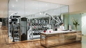 Une salle de sport moderne équipée de matériel d’exercice, dotée d’un comptoir d’accueil et d’un grand miroir qui reflète l’espace.