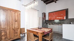 Una cucina compatta con elettrodomestici moderni, una zona pranzo con tavolo e sedie in legno e un grande armadio in legno.