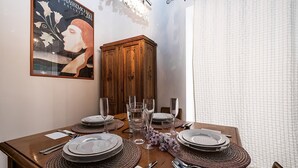 Un tavolo imbandito con piatti, posate e bicchieri, con un mobile in legno e un poster sullo sfondo.
