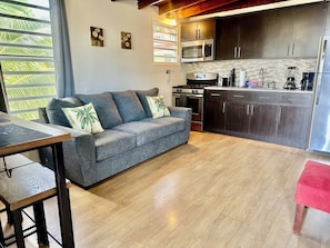 A modern kitchen with dark cabinets, a stainless steel refrigerator, and a built-in microwave. - Kasa Maui - Ocean View Apartment - 1 Minute From Sandy Beach!! (Rincon)