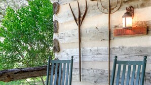 Una cabaña rústica de madera con dos mecedoras y una pequeña mesa en un porche de madera.