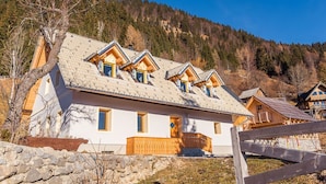 Et chalet-lignende hus med skråtag, mange vinduer og en stensokkel.