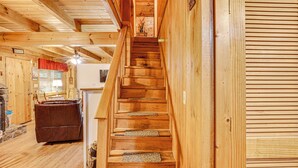 A wooden staircase in a cabin with a fireplace and a leather sofa. - Large Mountain Creek! Cabin in Tellico Plains (Tellico Plains)