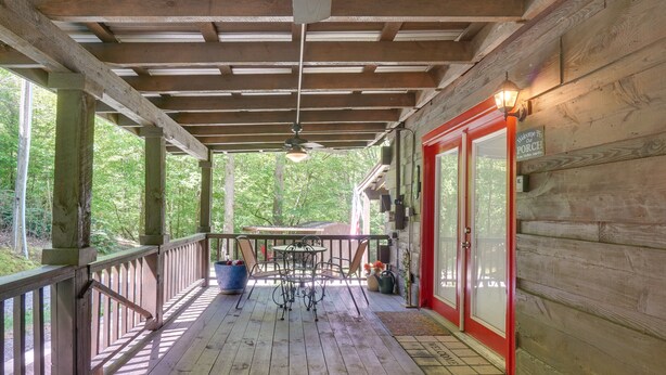 A wooden deck with a railing, a table with chairs, and a door with a sign. - Large Mountain Creek! Cabin in Tellico Plains (Tellico Plains)
