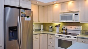 Una cocina moderna con electrodomésticos de acero inoxidable, armarios blancos y microondas integrado.