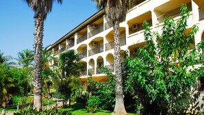 Hotel de vários andares com varandas, rodeado por vegetação exuberante e palmeiras.