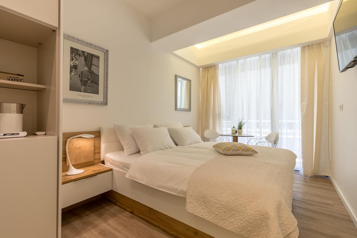 A modern bedroom with a bed, bedside table, lamp, and a framed picture on the wall.