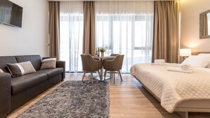 Et moderne hotelværelse med en seng, en sofa, et spisebord med stole og et fjernsyn.